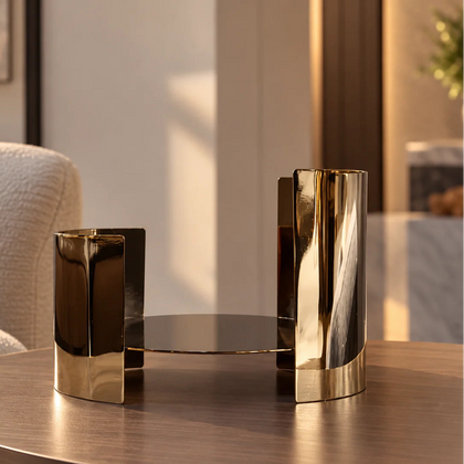 Contemporary metallic pedestal stand with curved design and reflective finish.