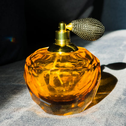 Luxury amber glass perfume sprayer accent with vintage atomizer bulb and faceted crystal-inspired detailing for elegant vanity decor