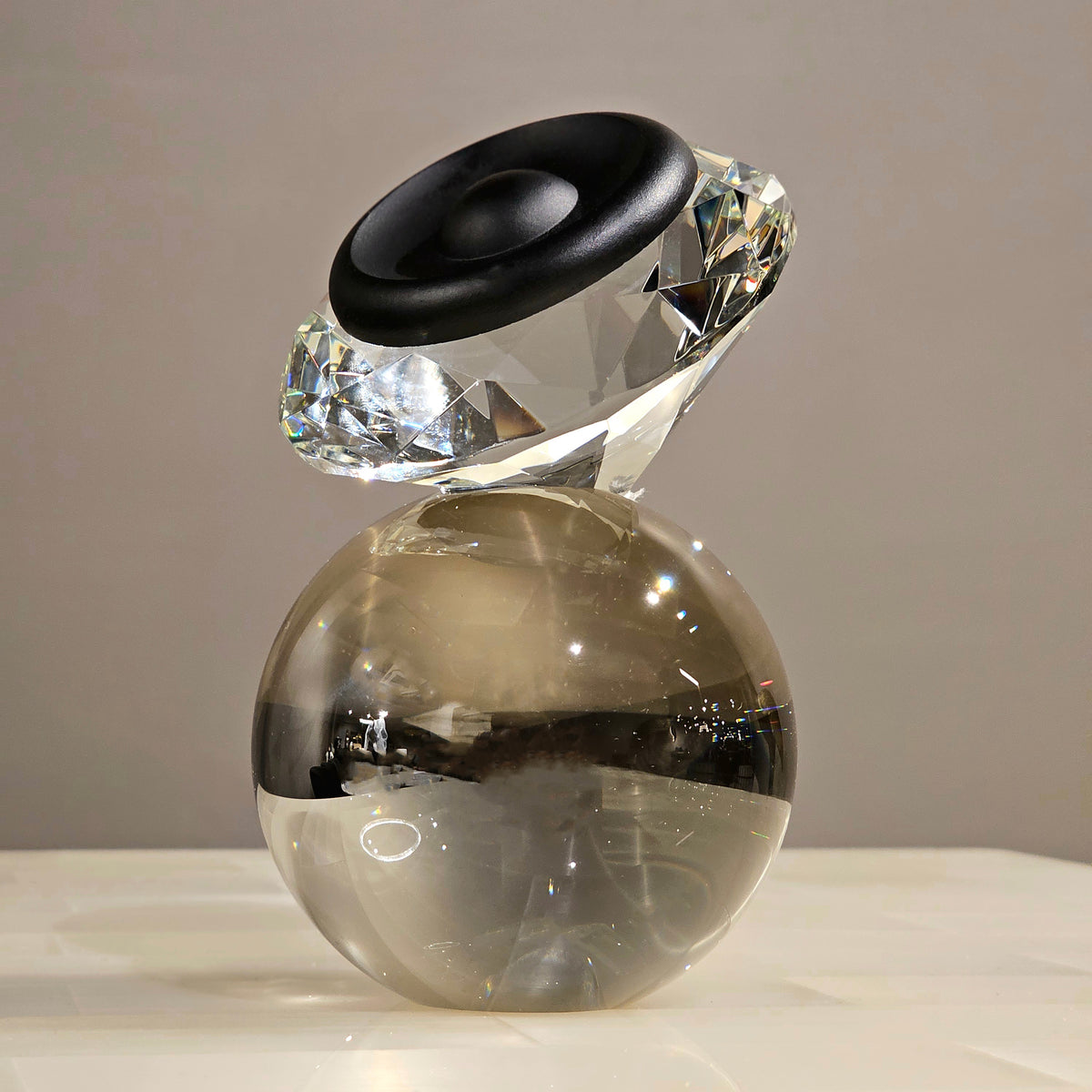 Luxury crystal decorative accent featuring a faceted crystal element balanced on a smoked crystal sphere with contemporary geometric styling, ideal for coffee tables, consoles, offices and modern designer interiors.