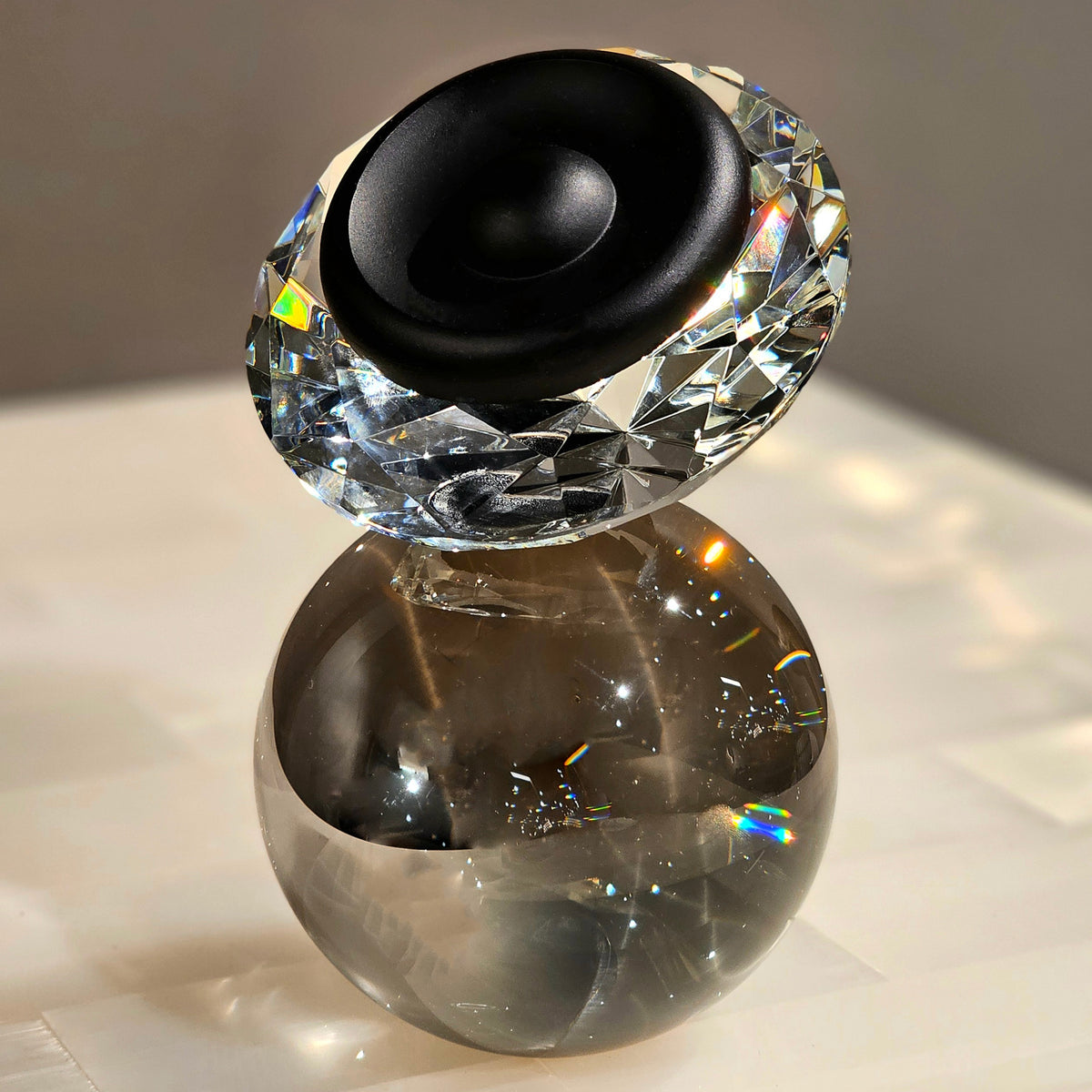 Luxury crystal decorative accent featuring a faceted crystal element balanced on a smoked crystal sphere with contemporary geometric styling, ideal for coffee tables, consoles, offices and modern designer interiors.