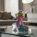 Luxury abstract geometric bust sculpture with reflective prism face detailing displayed on a modern glass coffee table in a contemporary living room