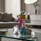 Luxury abstract geometric bust sculpture with reflective prism face detailing displayed on a modern glass coffee table in a contemporary living room