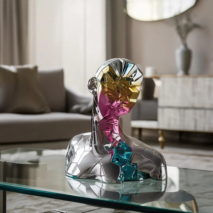 Luxury abstract geometric bust sculpture with reflective prism face detailing displayed on a modern glass coffee table in a contemporary living room