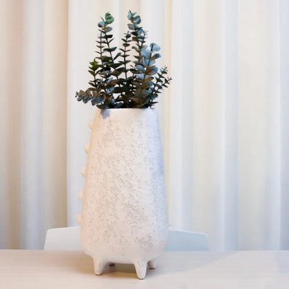 Designer white decorative vase styled with fresh flowers on a wooden table in a contemporary living space