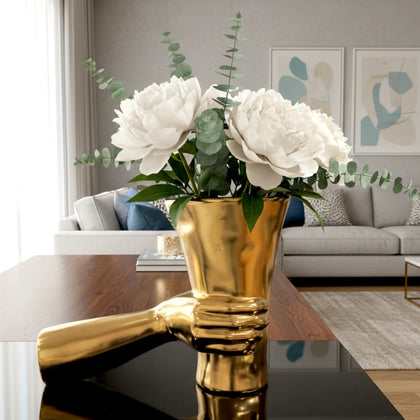 Modern gold hand shaped flower vase with white floral arrangement on luxury tabletop setting