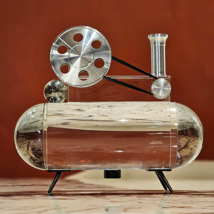 Film reel inspired decor piece with metal wheel and glass base, cinematic themed tabletop accent for home bar, studio or modern interior styling