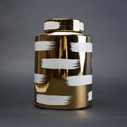 Gold decorative metal jar with white brushstroke design and matching lid