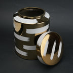 Gold decorative metal jar with white brushstroke design and matching lid
