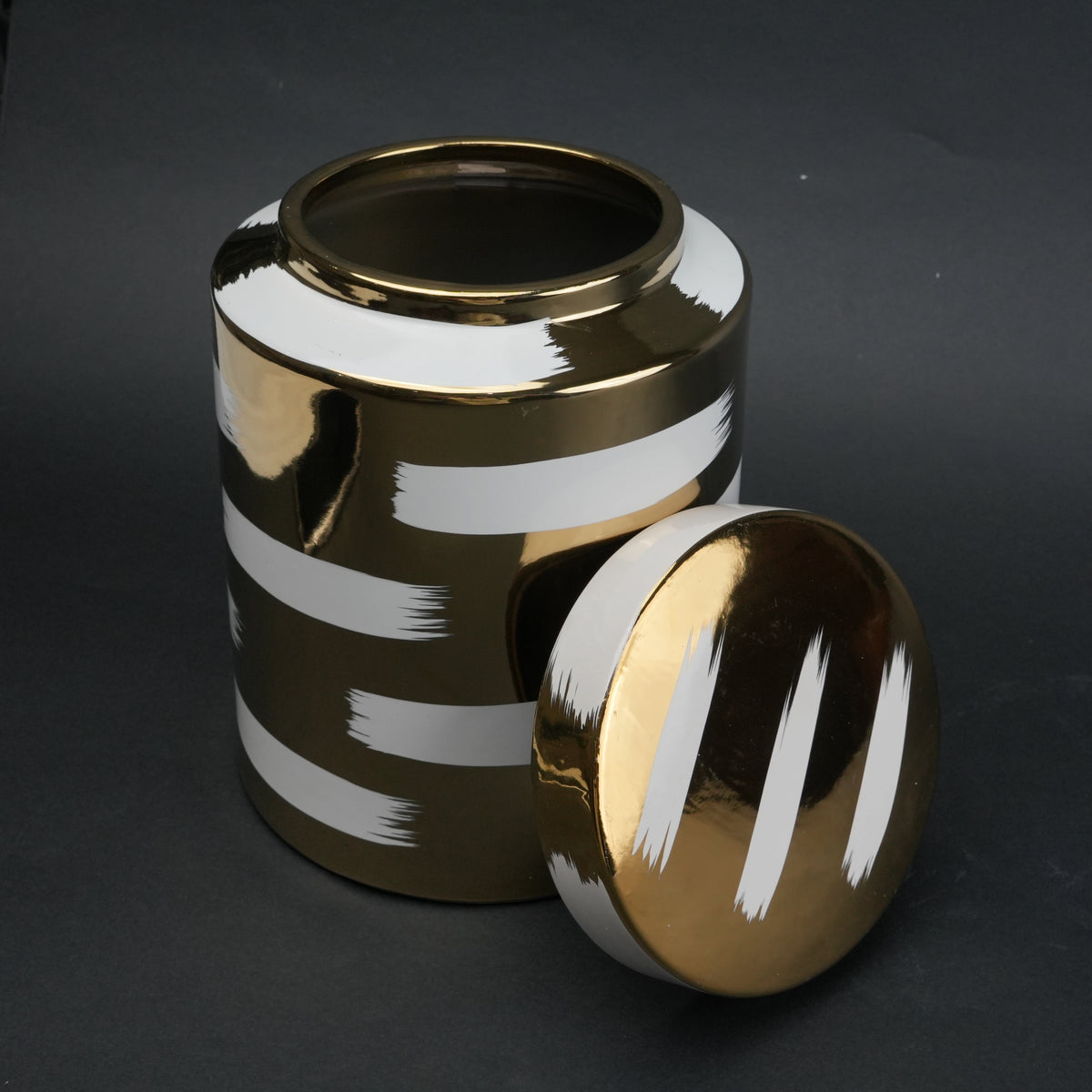 Gold decorative metal jar with white brushstroke design and matching lid