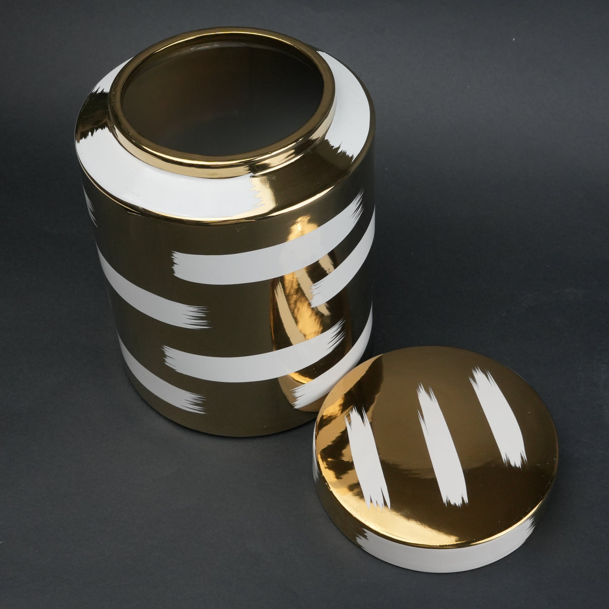 Gold decorative metal jar with white brushstroke design and matching lid