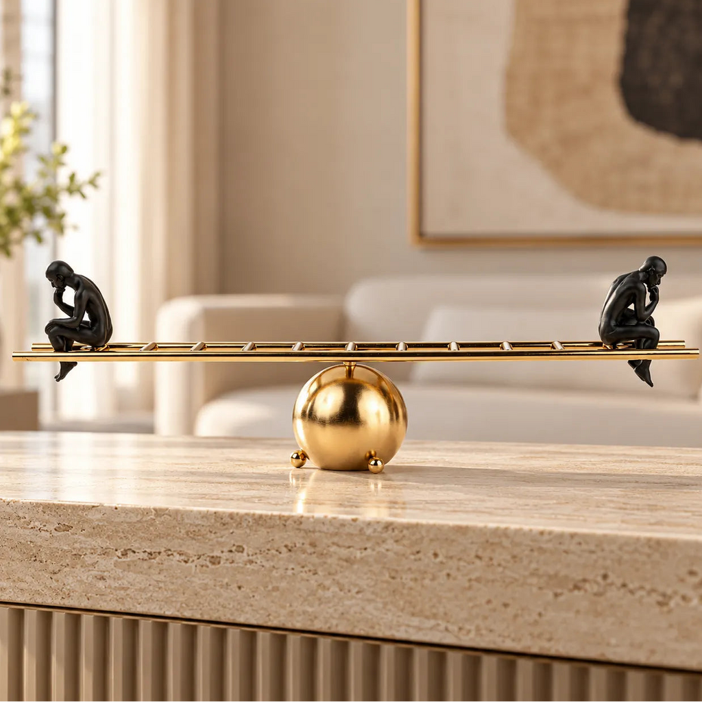 Two black contemplative figurines on a gold ladder-inspired decorative sculpture.