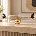 Two black contemplative figurines on a gold ladder-inspired decorative sculpture.