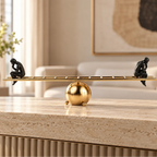 Two black contemplative figurines on a gold ladder-inspired decorative sculpture.