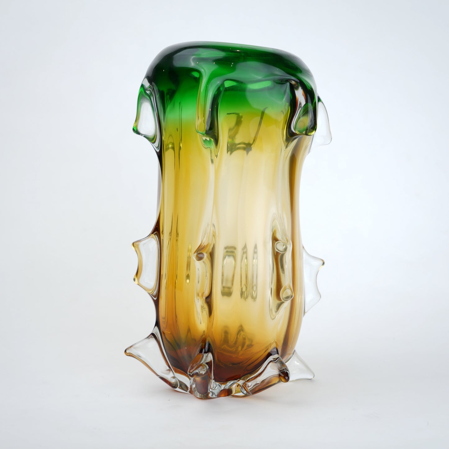 Glass vase with gradient green to amber color on a white background