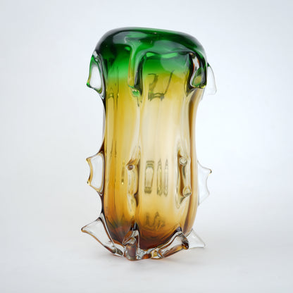 Glass vase with gradient green to amber color on a white background