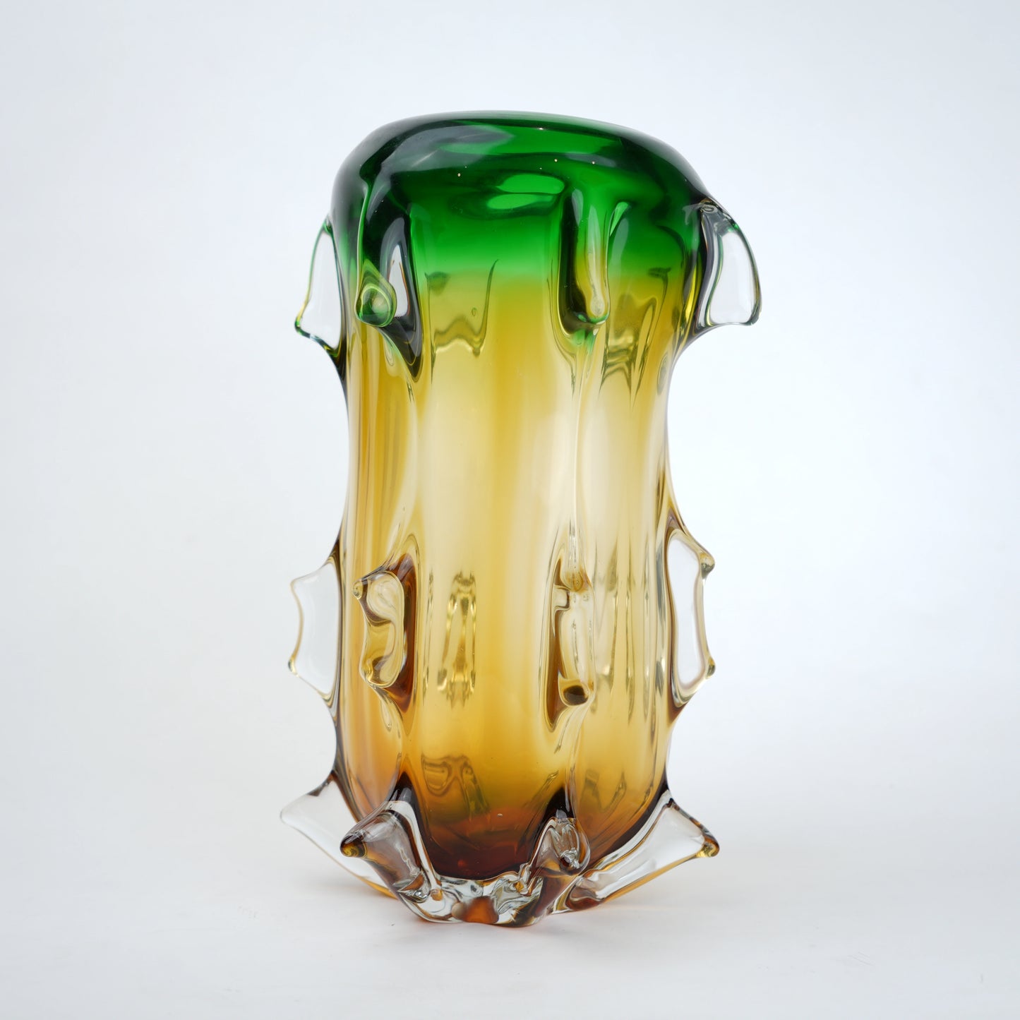 Glass vase with gradient green to amber color on a white background