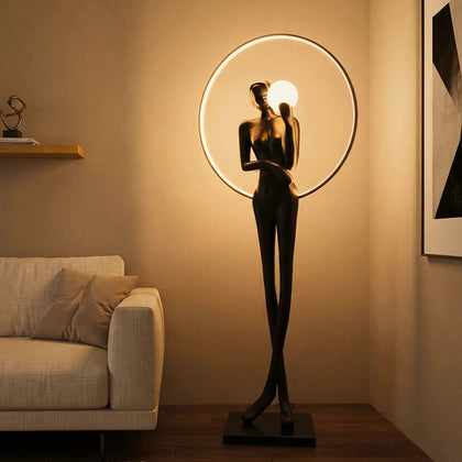 Tall matte-black lady sculpture floor lamp with glowing halo ring and warm globe light