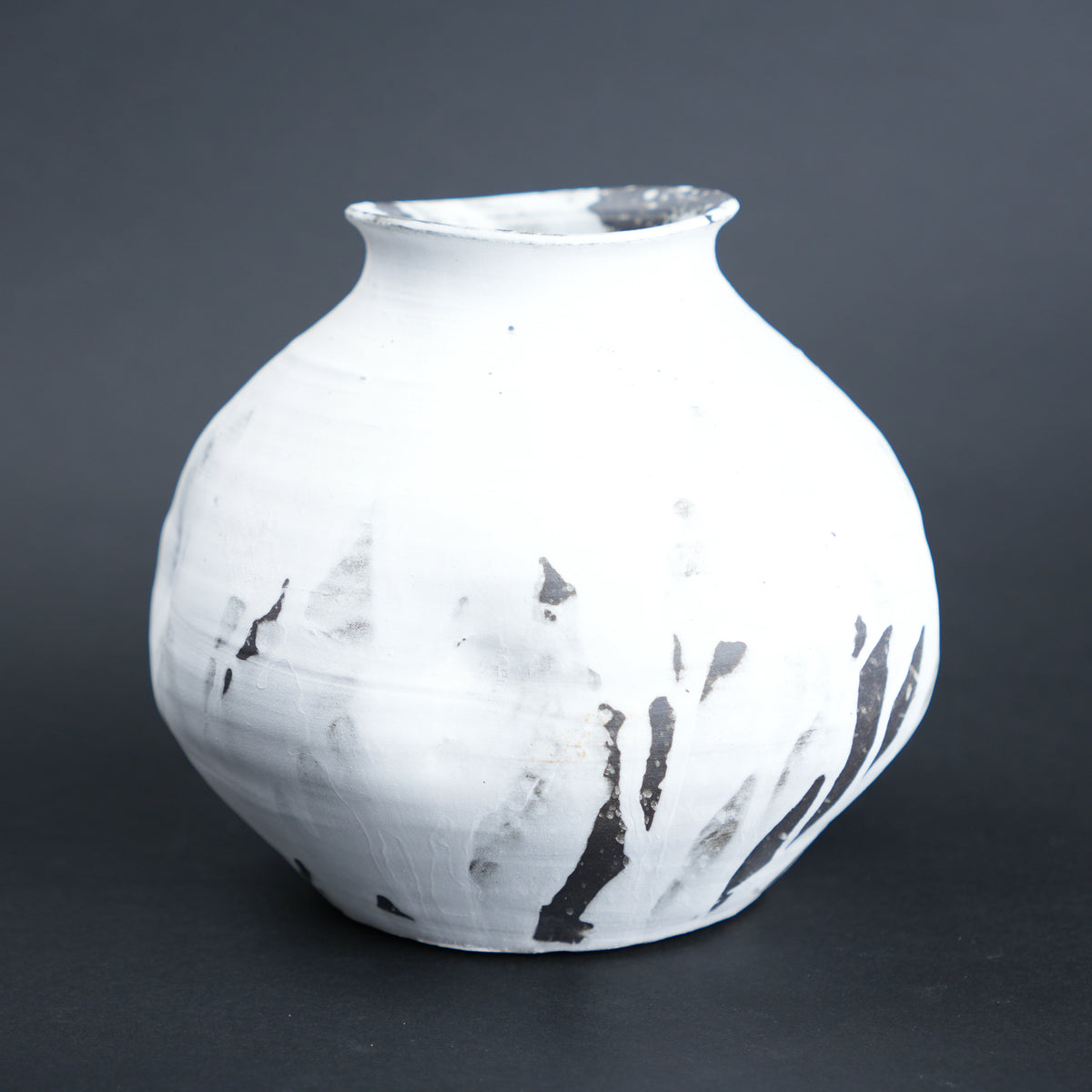 White ceramic vase with black abstract patterns on a dark gray background