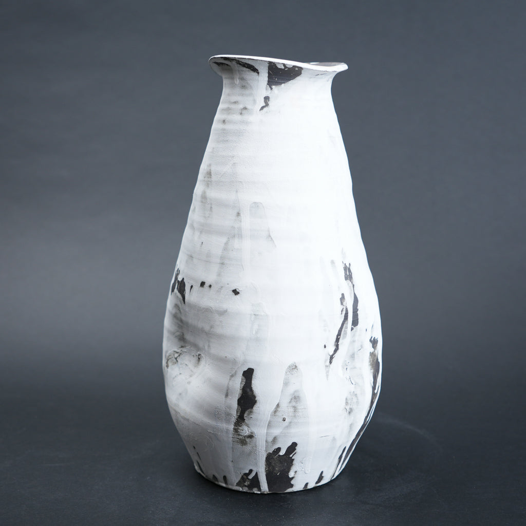 White ceramic vase with black marbled patterns on a dark gray background