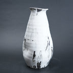 White ceramic vase with black marbled patterns on a dark gray background