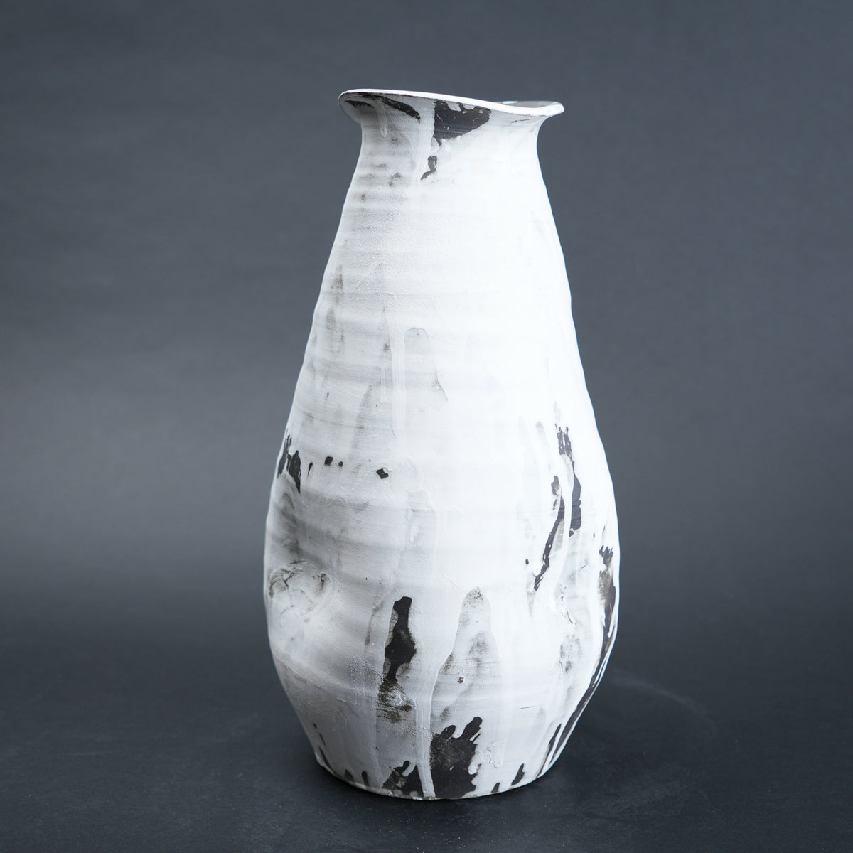 White ceramic vase with black marbled patterns on a dark gray background
