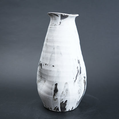 White ceramic vase with black marbled patterns on a dark gray background