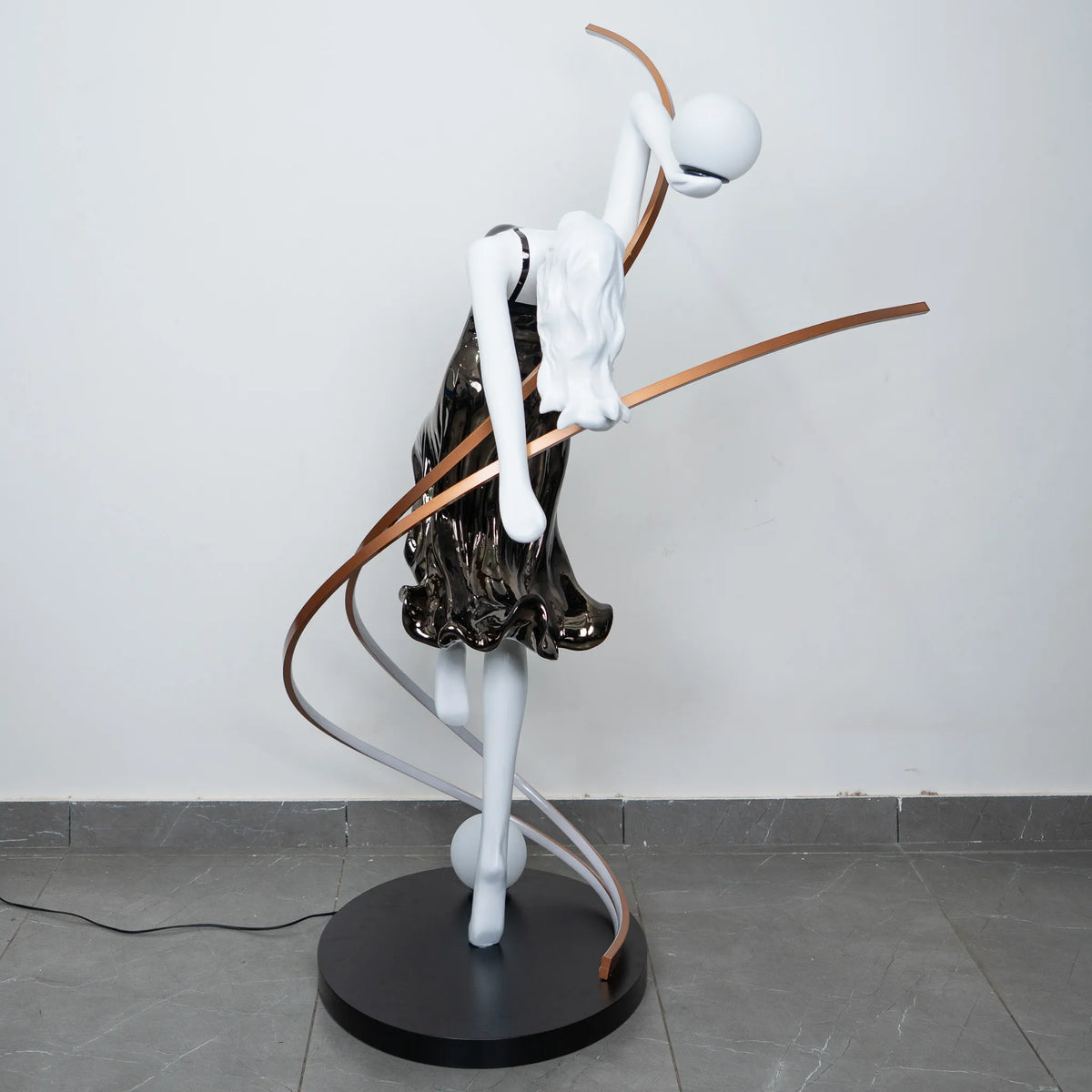 Black and white human figure floor lamp with bronze curved accents and round black base