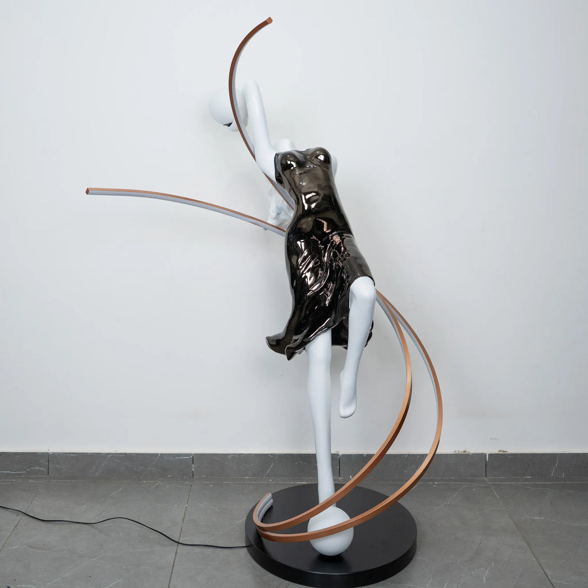 Black and white human figure floor lamp with bronze curved accents and round black base