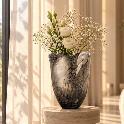 Decorative smoked glass vase with abstract black swirl detailing and floral arrangement.