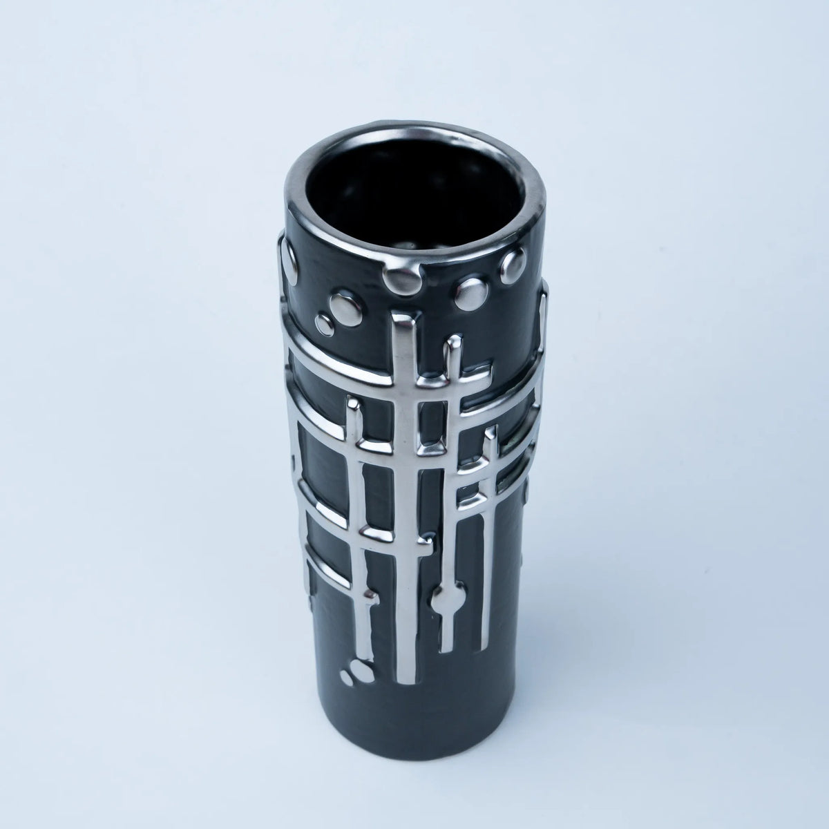 A modern black ceramic vase with a textured silver metallic grid pattern and small raised circular accents, shown on a light gray background.