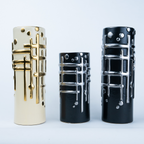 Three cylindrical decorative vases with a modern geometric design, shown in cream, black, and glossy black sizes against a light gray background.