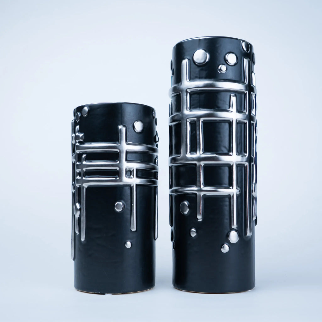 Two black ceramic vases with a glossy finish and raised silver geometric patterns, displayed on a light gray background.