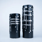 Two black ceramic vases with a glossy finish and raised silver geometric patterns, displayed on a light gray background.