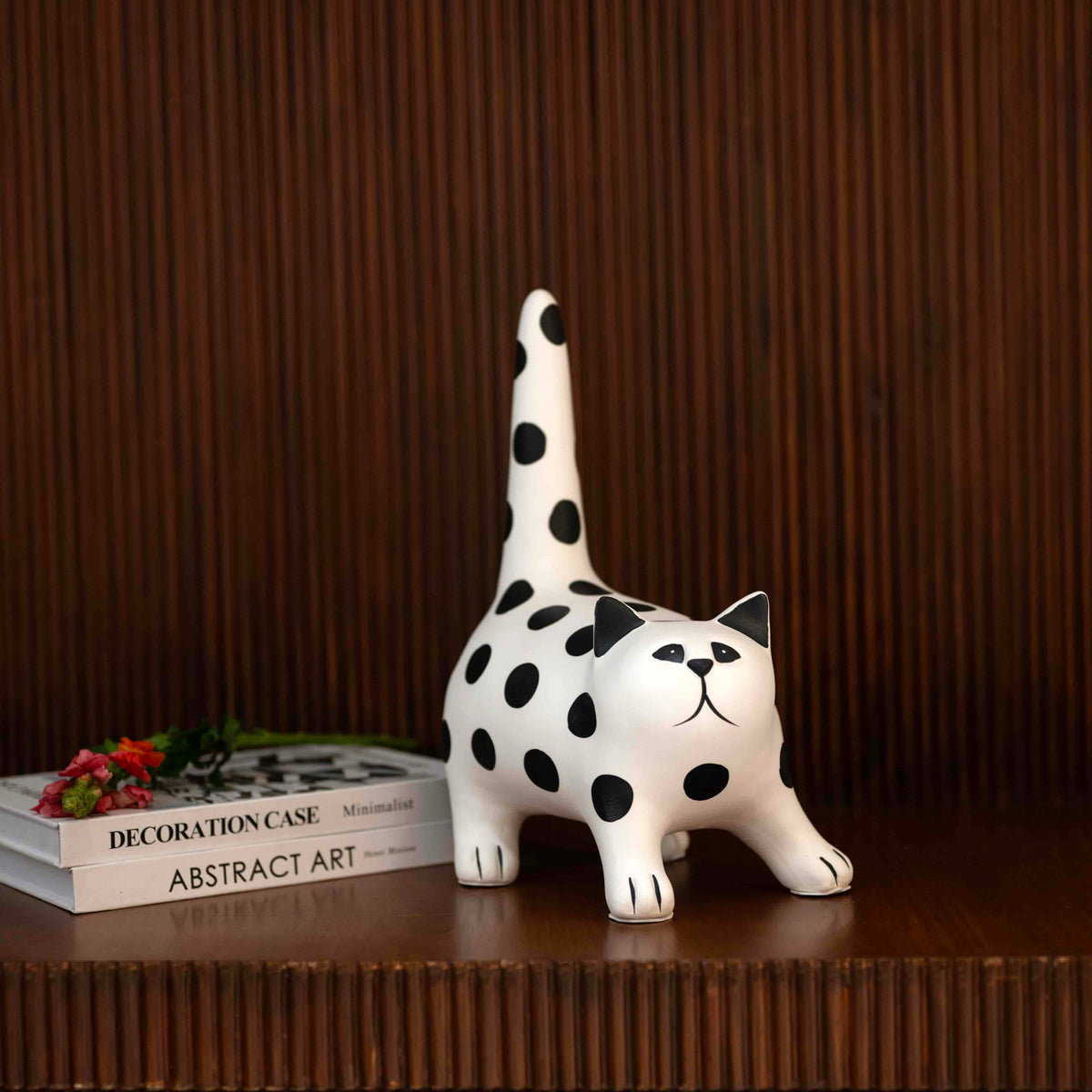 White polka dot cat figurine in stretched pose with raised tail on tabletop décor setting