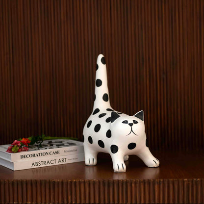 White polka dot cat figurine in stretched pose with raised tail on tabletop décor setting