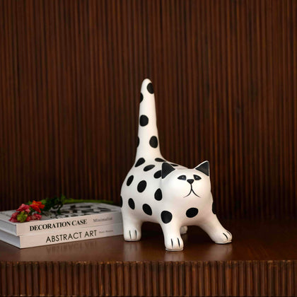 White polka dot cat figurine in stretched pose with raised tail on tabletop décor setting