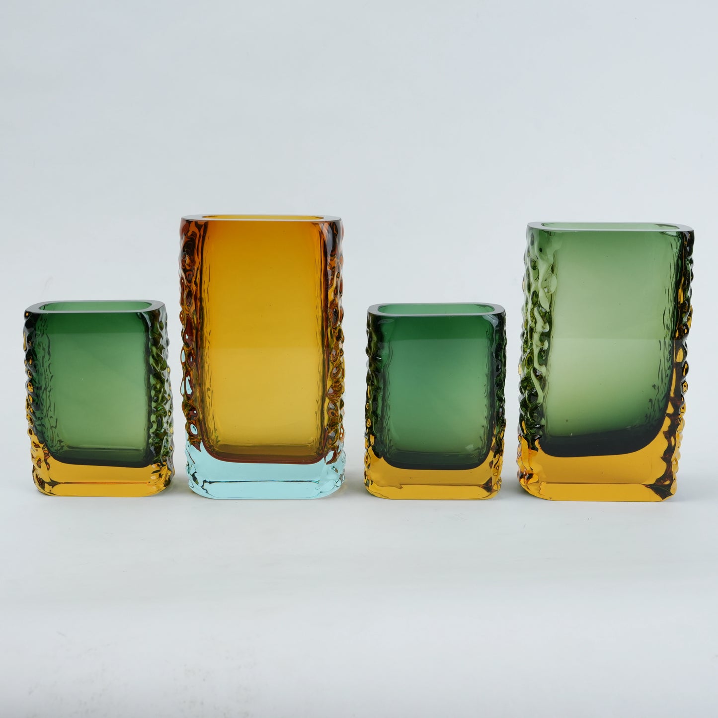 Set of four colorful glass vases on a light gray background