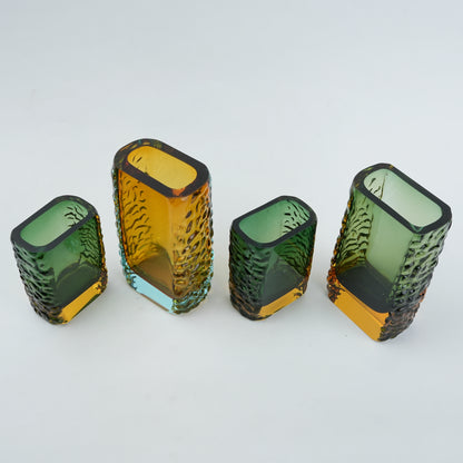 Four textured glass vases in green and yellow on a white background