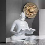 Glossy white reading sculpture lamp with abstract seated figure holding a book and built-in LED light.