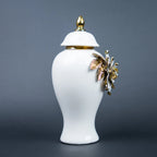 White ceramic jar with gold leaf design and lid on a