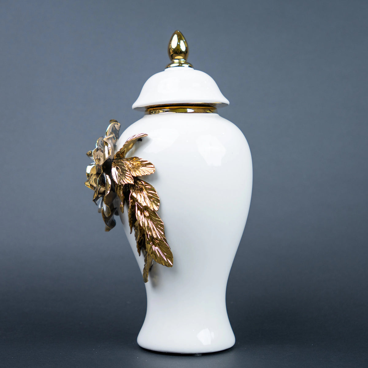 White ceramic jar with gold leaf design and lid on a