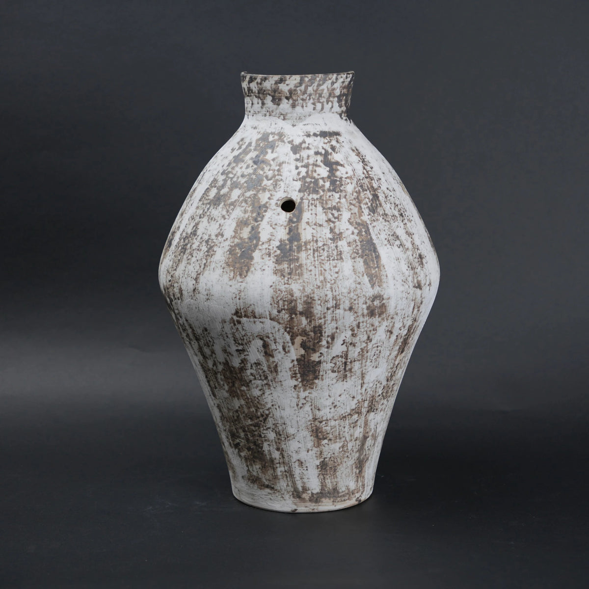 Vintage-style ceramic vase with a textured surface on a dark background