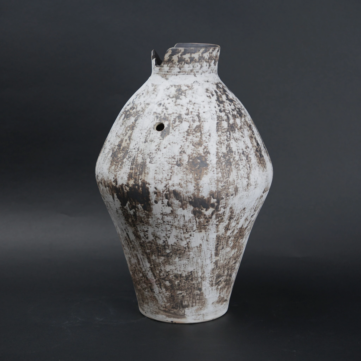 Vintage ceramic vase with a textured surface on a dark background
