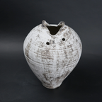 White distressed ceramic vase with rounded body and narrow base, featuring a textured rustic finish, dual side openings, and an uneven top rim, ideal for modern home decor and artistic styling.