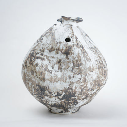 White distressed ceramic vase with rounded body and narrow base, featuring a textured rustic finish, dual side openings, and an uneven top rim, ideal for modern home decor and artistic styling.