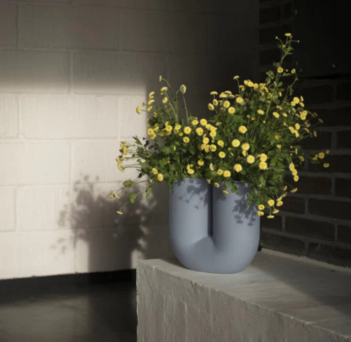 Light blue dual curve vase w/ daisies