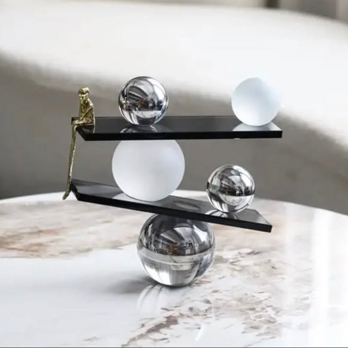 Abstract balancing sculpture with chrome spheres and a small gold figurine