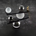 Abstract balancing sculpture with chrome spheres and a small gold figurine