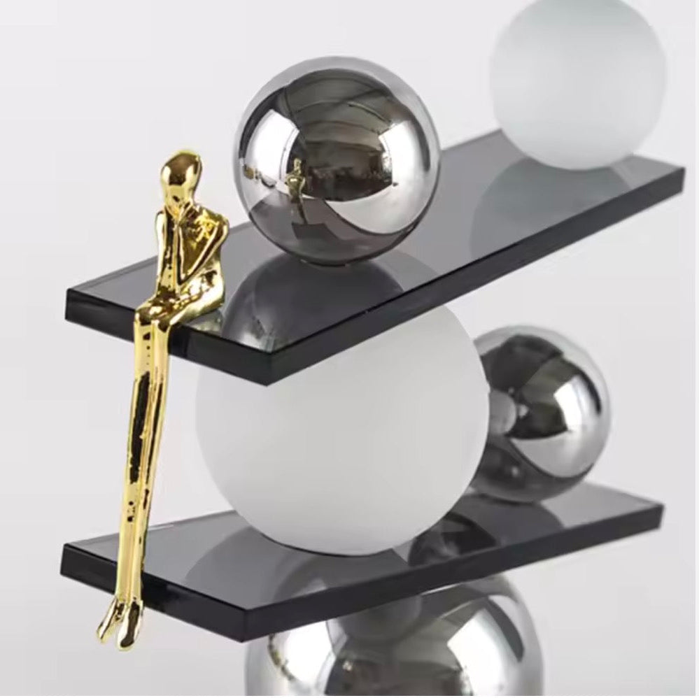 Abstract balancing sculpture with chrome spheres and a small gold figurine
