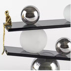 Abstract balancing sculpture with chrome spheres and a small gold figurine